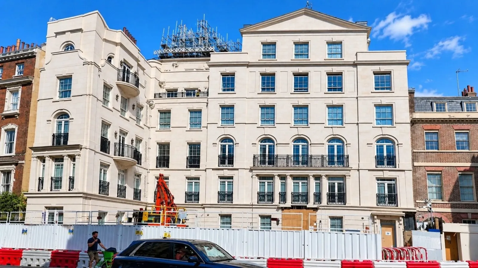 Stucco building under scaffold with hoarding at street level
