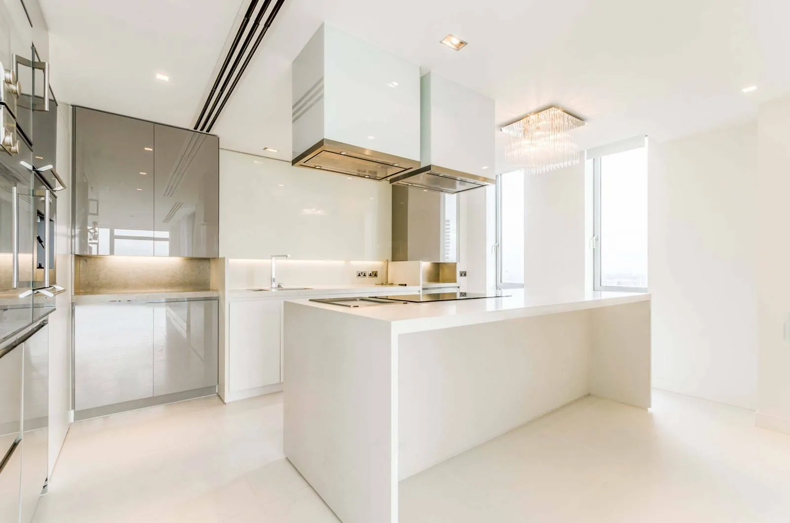White modern kitchen with a long island and a glass extractor hood in a Canary Wharf penthouse