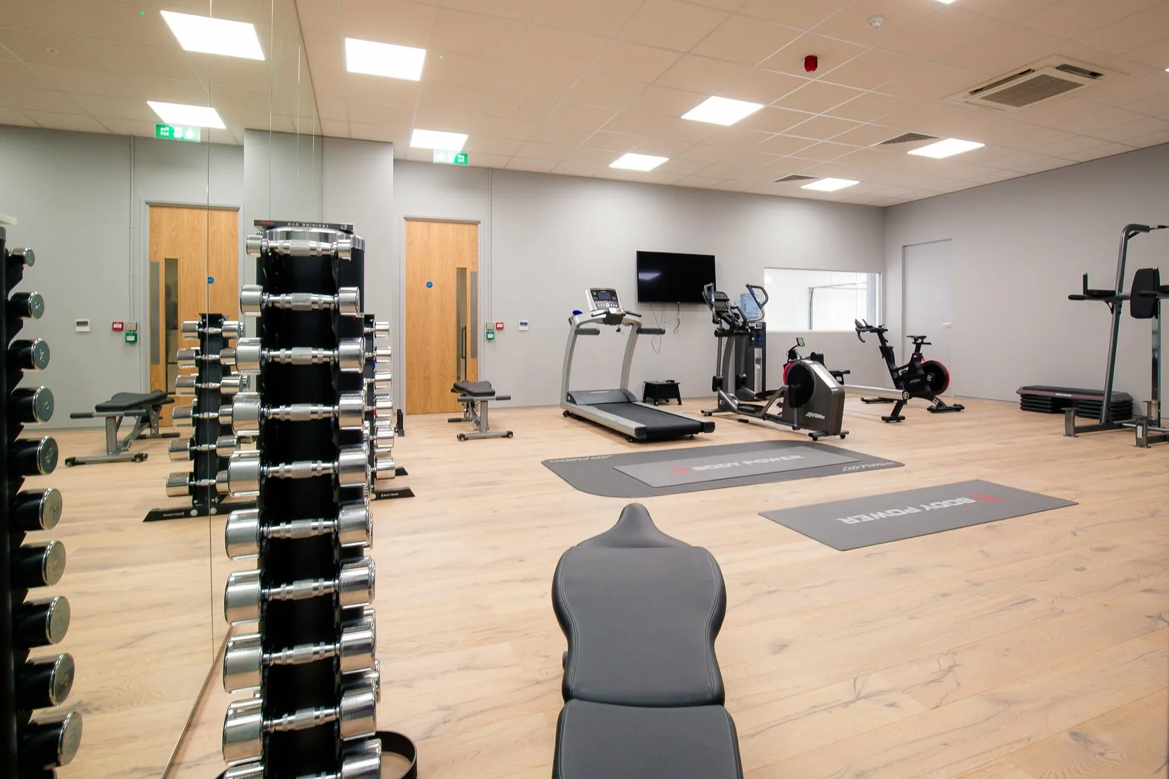 Finished gym in Banbury with a timber floor, mirrored wall and training equipment, designed and built by Craftex