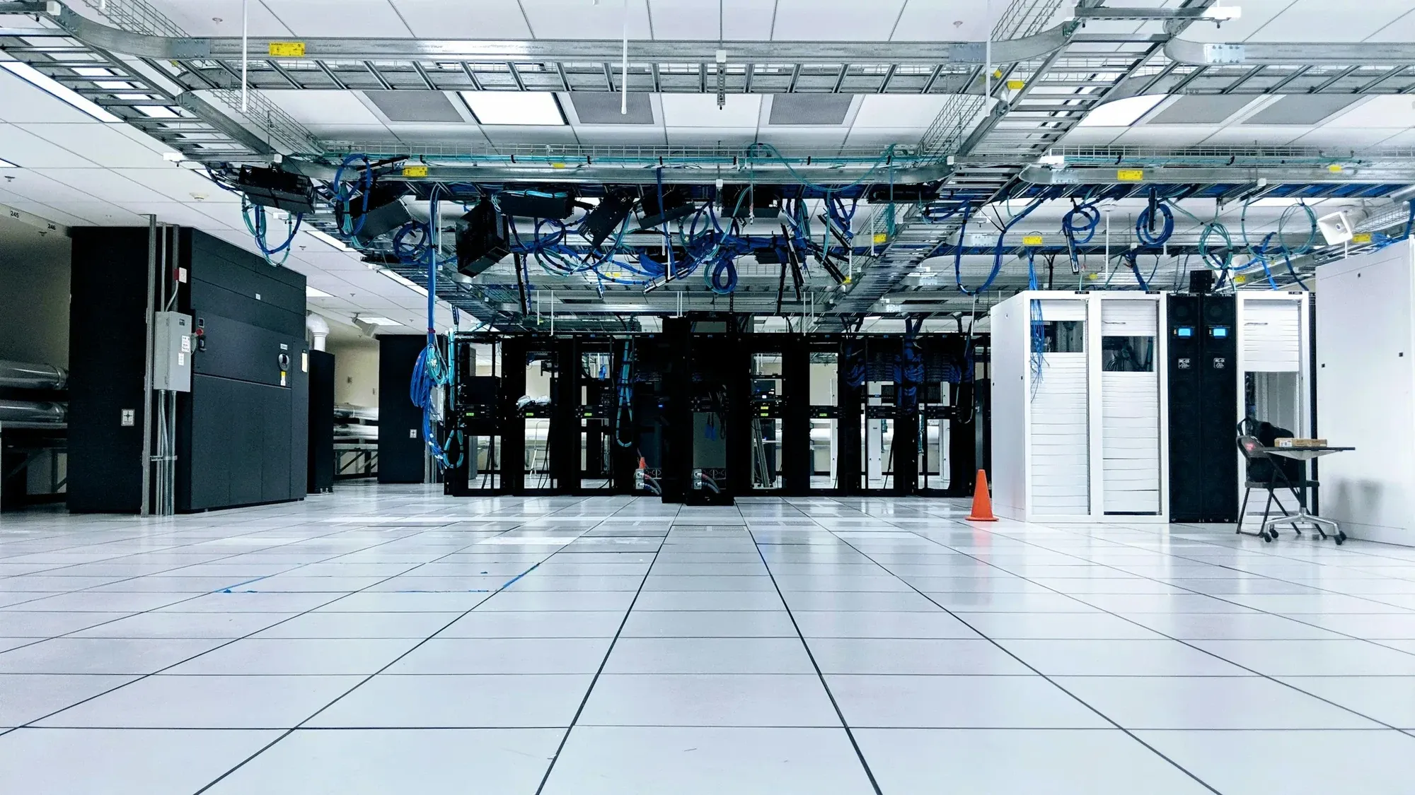Server hall with rows of cabinets, overhead cable trays and a raised access floor