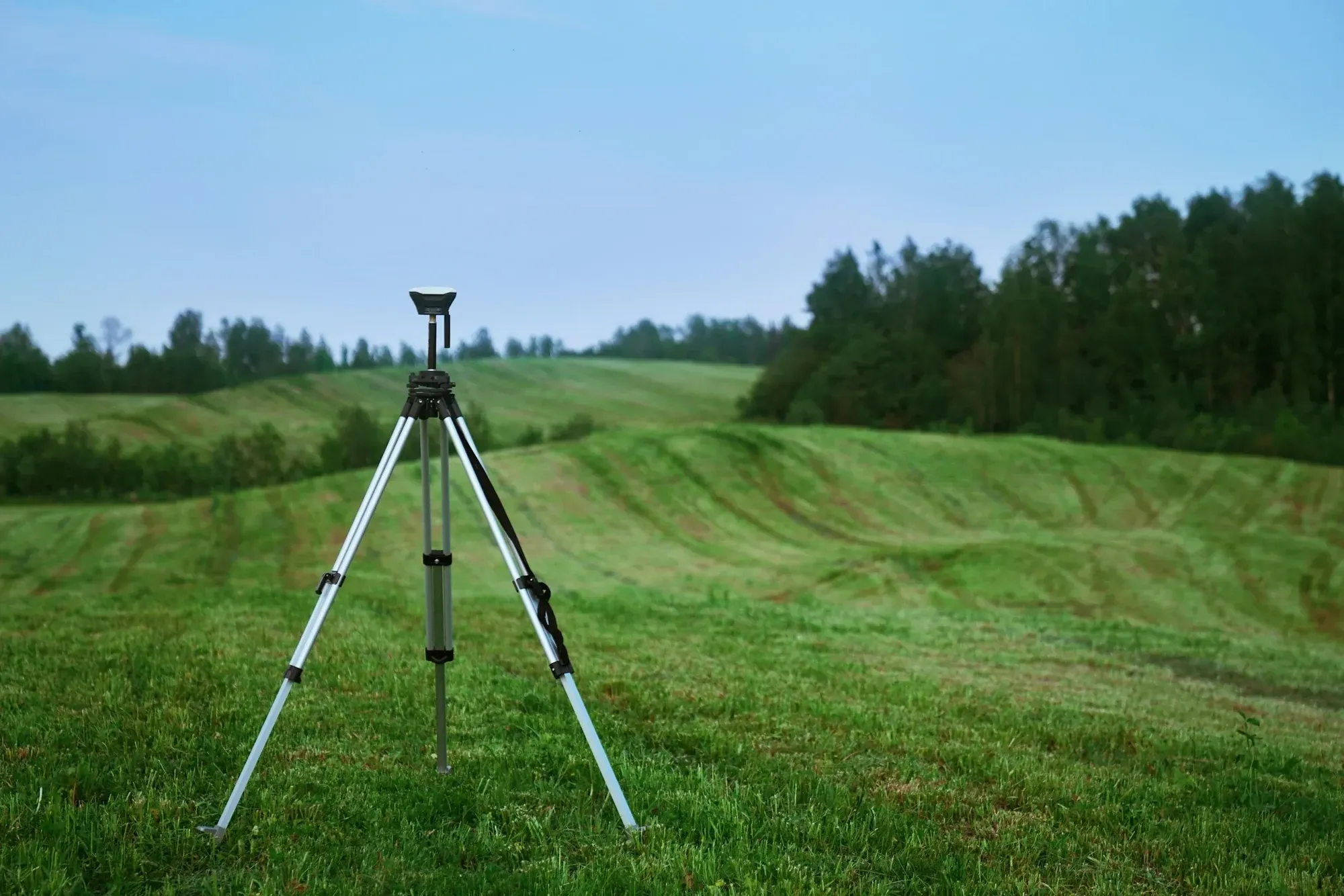 Surveying tripod and GPS receiver standing on a green field