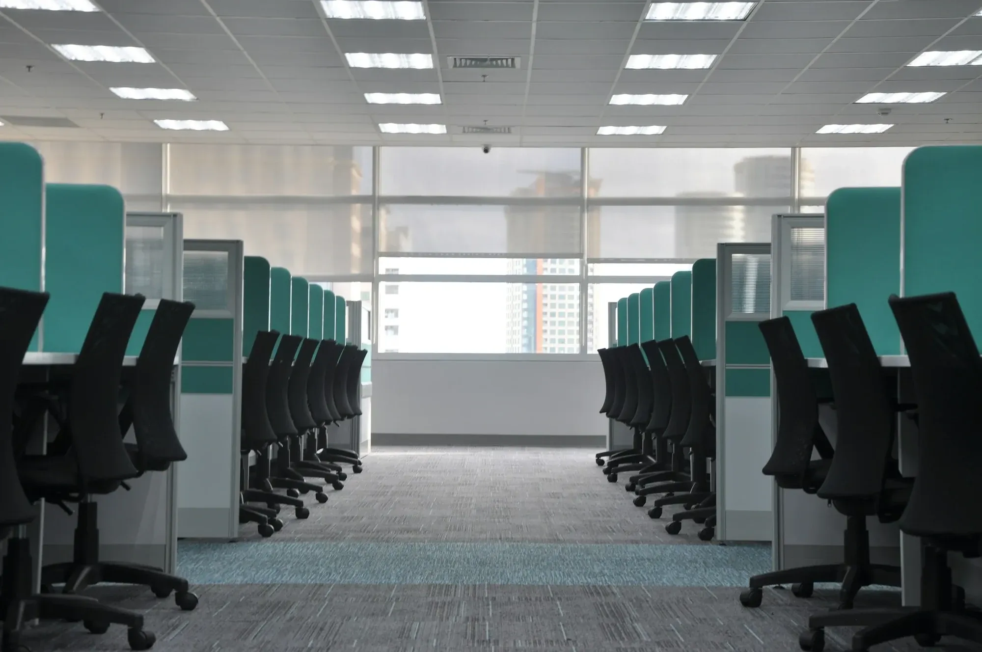 Empty office floor with rows of black chairs and desk screens
