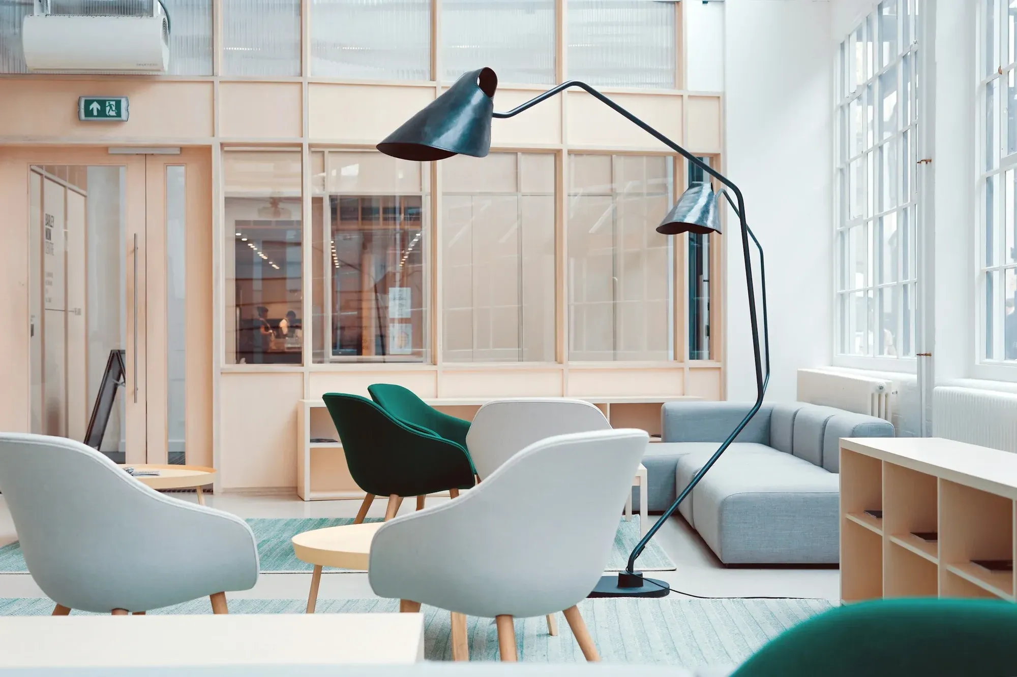 Bright office breakout area with glazed meeting rooms, soft seating and tall windows