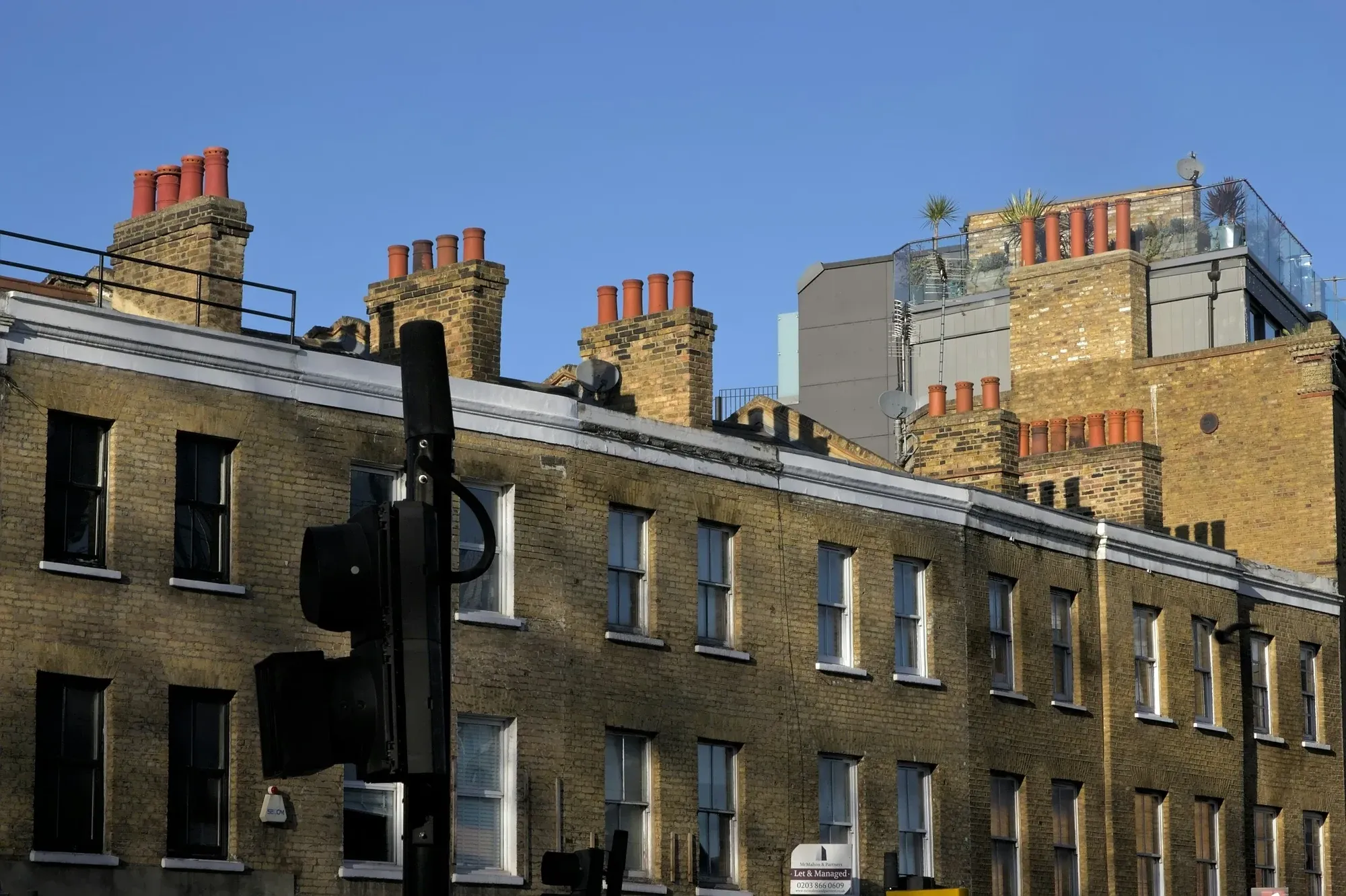 Yellow-brick London terrace with chimney stacks and a later storey added on the roof