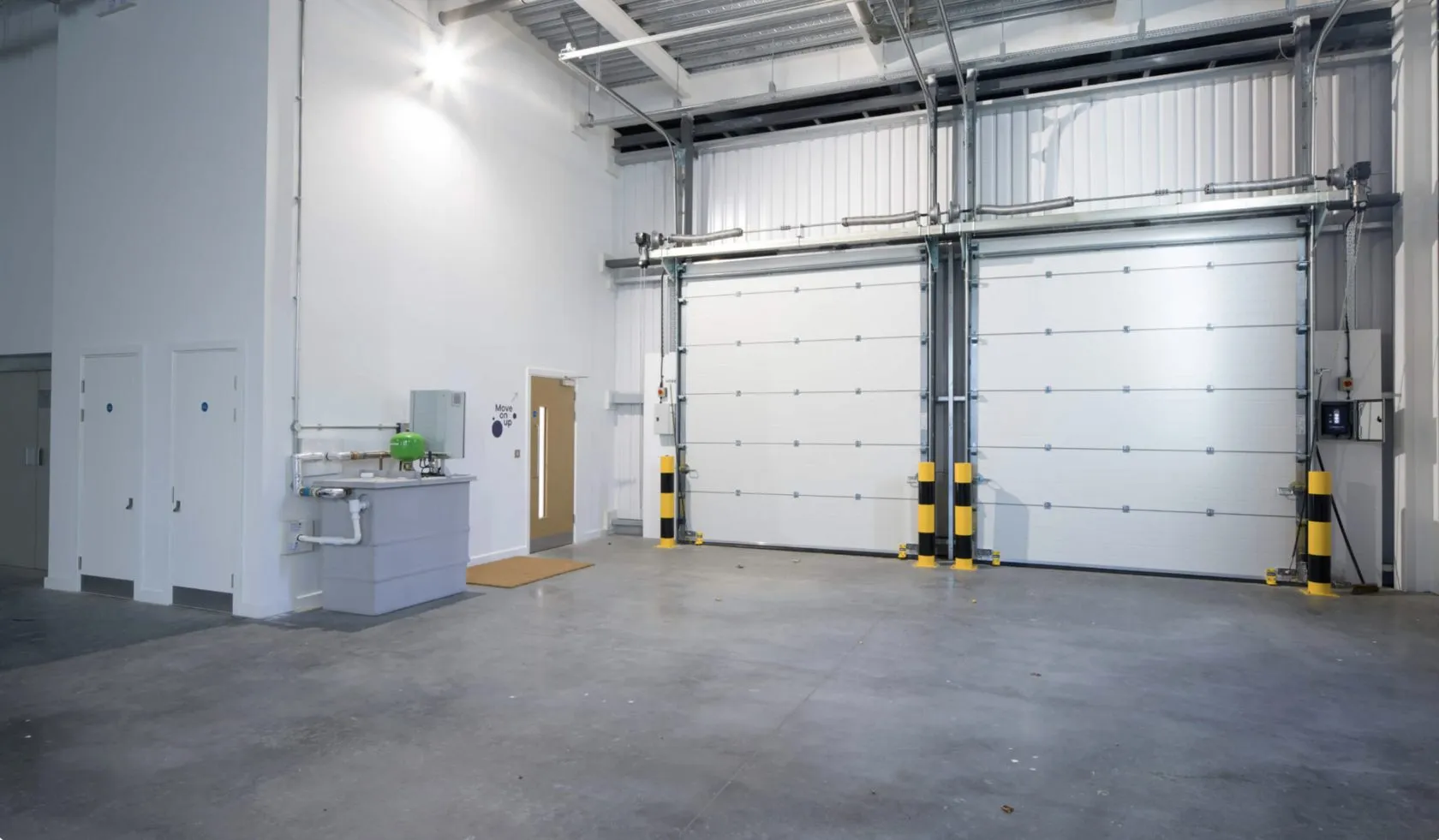 Fitted-out warehouse unit with two insulated loading doors, safety bollards, a sink and new internal doors in Hackney